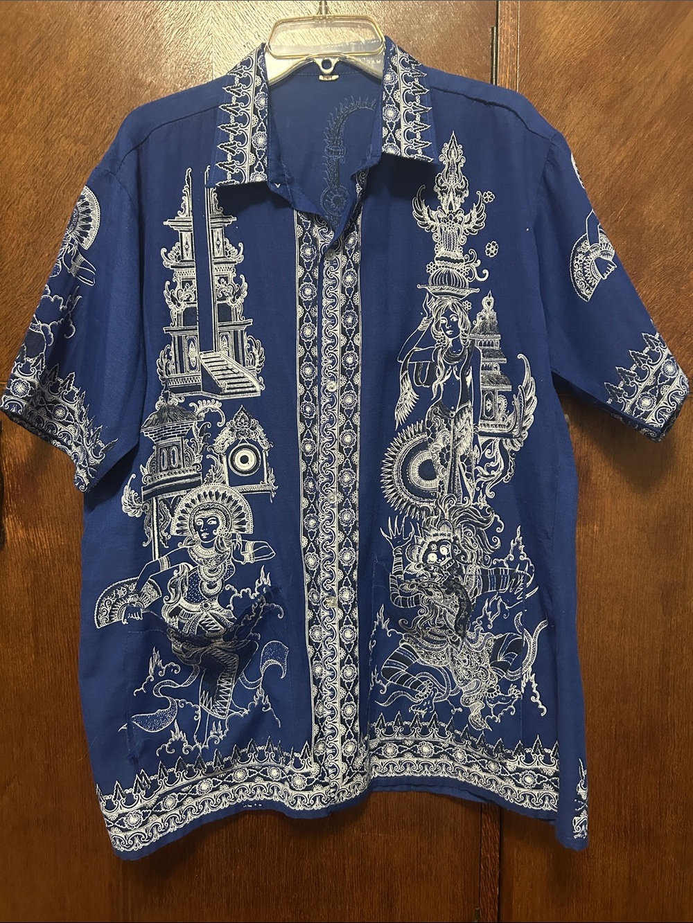 Blue button-up shirt features intricate white Balinese temple and dancer motifs